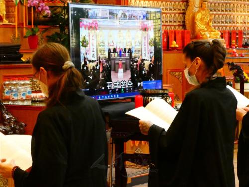 佛子們捧持《三皈五戒儀軌》，於大殿佛前跟著直播屏幕參與莊嚴典禮