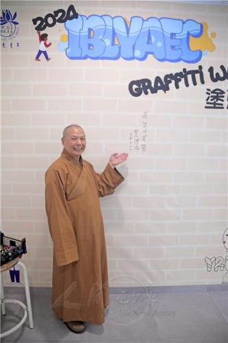 會設計一面「佛光塗鴉牆」，慧傳法師也在牆上，冩下主題「共生與共榮」