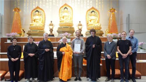 歡喜地拿著德文皈依證，與德文組學員於三寶佛前合影