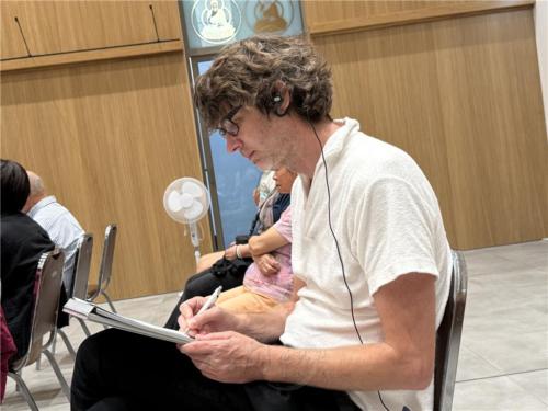 與會德國聽眾Lars透過同步口譯，專心記錄法師的開示內容