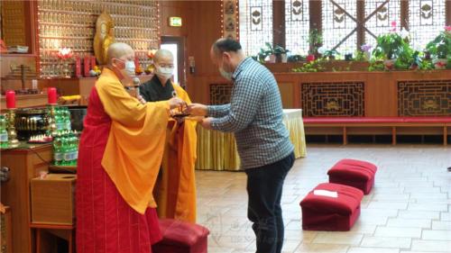 楊堯臣自妙祥法師手中接過皈依紀念品。